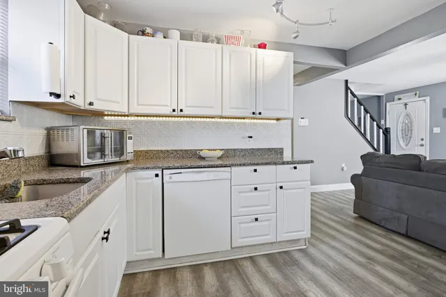 a kitchen with granite countertop white cabinets and white appliances