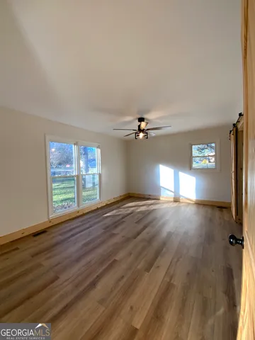 a view of empty room with wooden floor and fan
