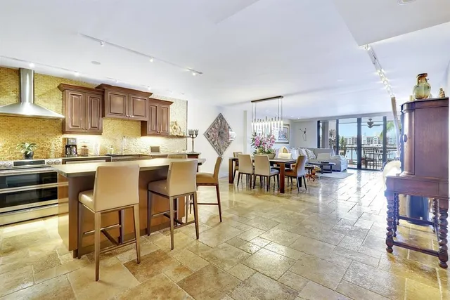 a open kitchen with granite countertop a stove a sink a dining table and chairs