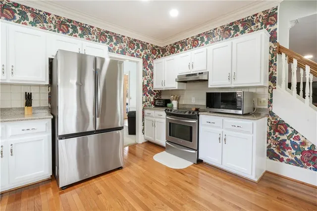 a kitchen with granite countertop stainless steel appliances a refrigerator sink and wooden floor