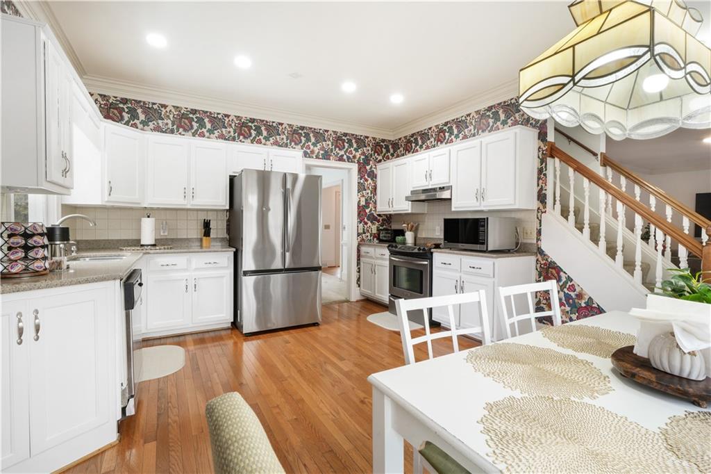 224 Rolling Oaks Drive Rome, GA 30165 - Photo 40 of 55 a kitchen with stainless steel appliances granite countertop a refrigerator a stove a sink dishwasher and white cabinets with wooden floor