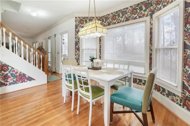 a kitchen with stainless steel appliances granite countertop a stove top oven a sink a dining table and chairs with wooden floor