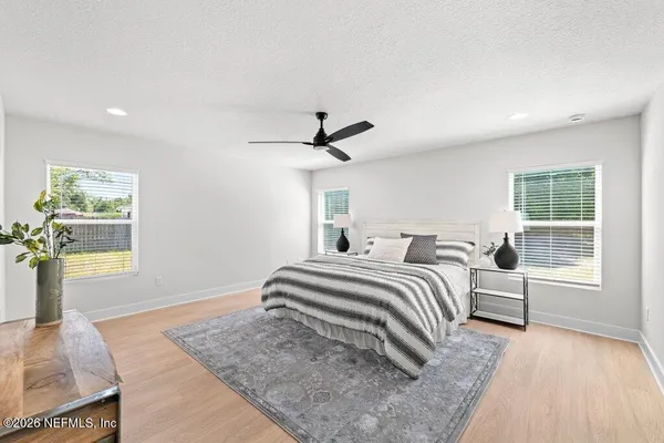 a spacious bedroom with a bed and wooden floor