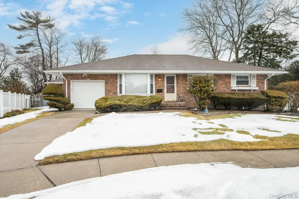 a front view of a house with a yard covered with snow and cars