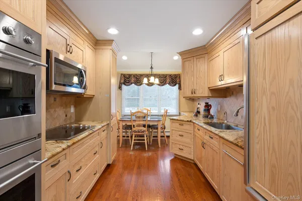 a kitchen with stainless steel appliances kitchen island granite countertop a stove a sink and white cabinets with wooden floor