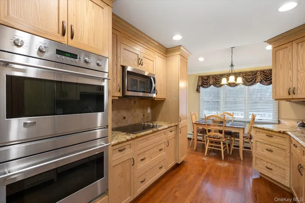 a kitchen with stainless steel appliances kitchen island granite countertop a stove cabinets and wooden floor