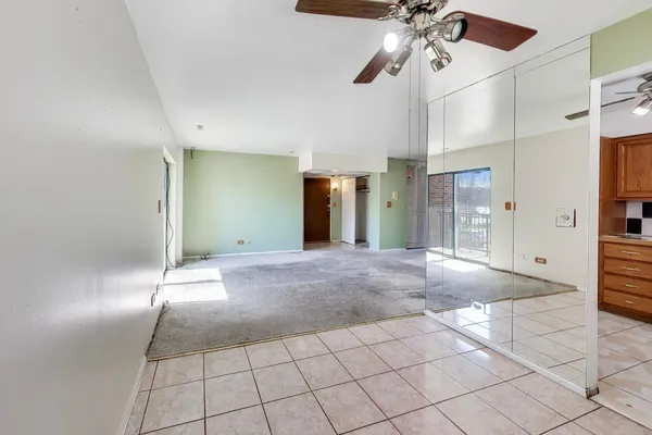 a view of a livingroom with a chandelier fan and kitchen space