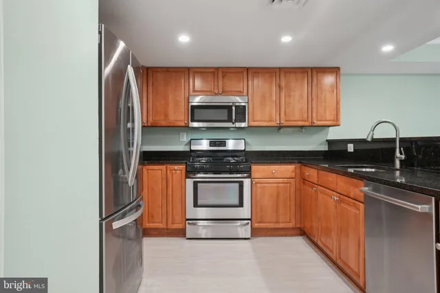 a kitchen with stainless steel appliances granite countertop a stove a sink and a refrigerator