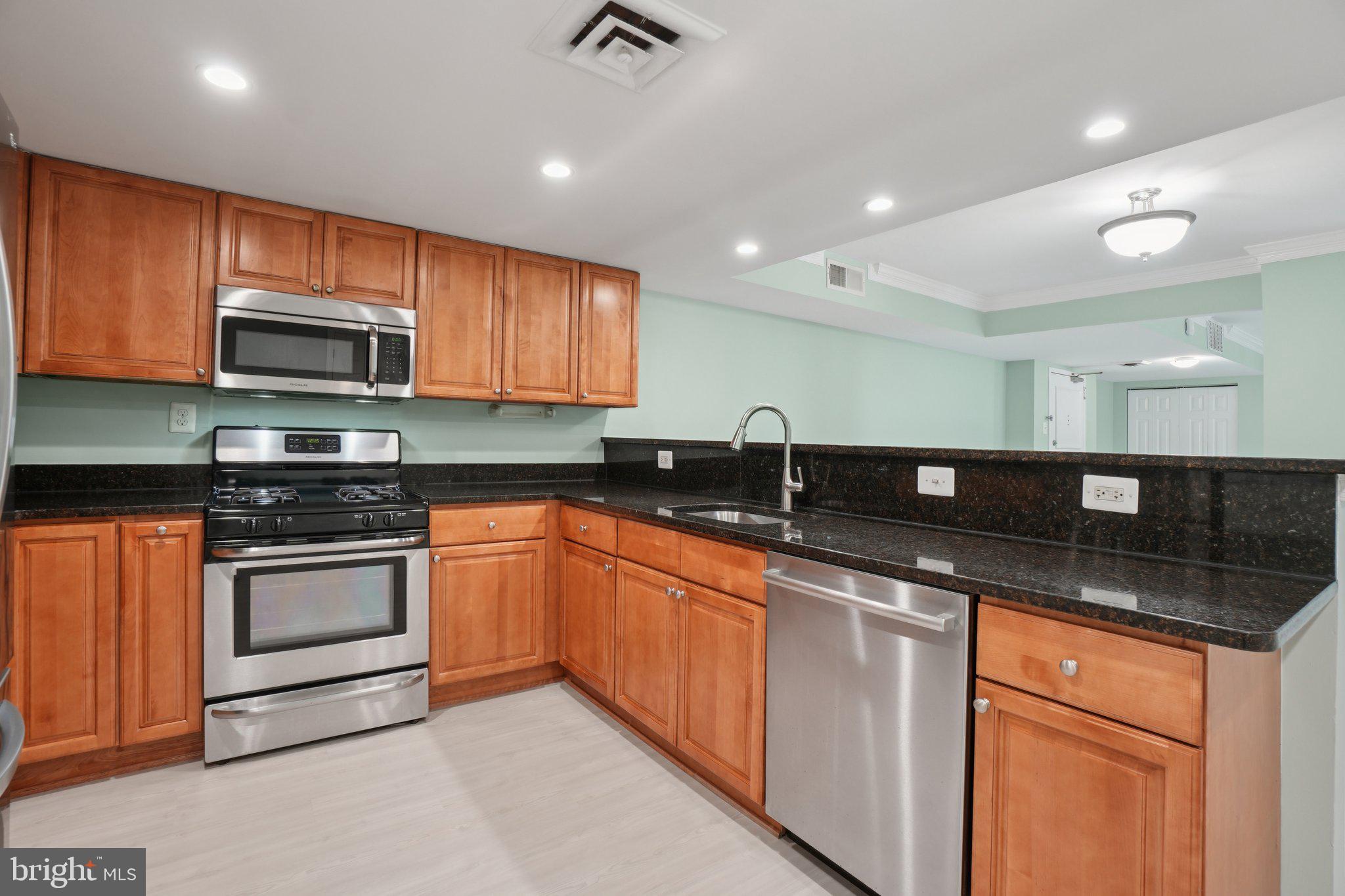 1515 South Arlington Ridge Road, Unit 603 Arlington, VA 22202 - Photo 7 of 39 a kitchen with stainless steel appliances granite countertop wooden cabinets a stove a sink and a microwave