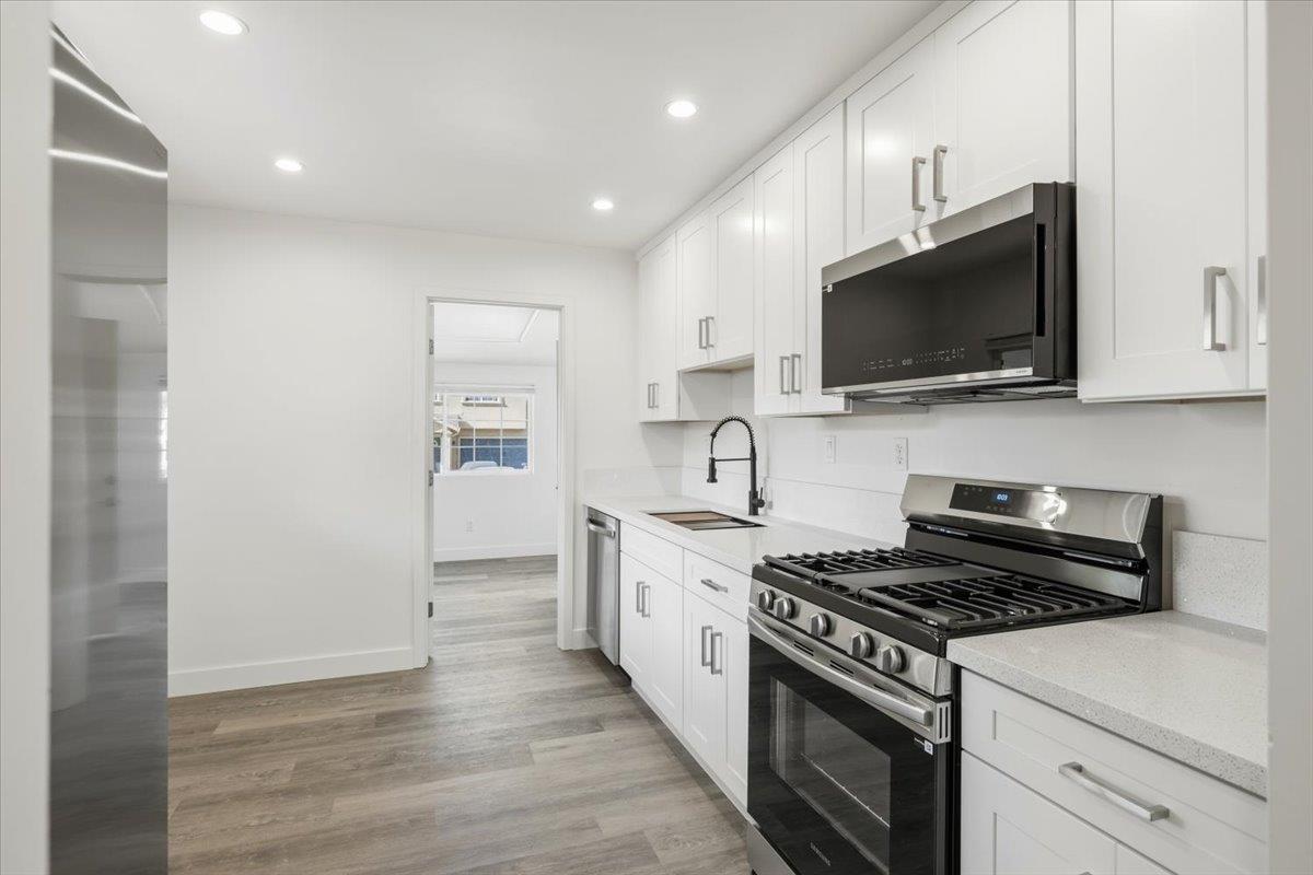 209 Dewitt Court Sacramento, CA 95838 - Photo 13 of 25 kitchen featuring stainless steel appliances, white cabinets, recessed lighting, light wood-style floors (LVP), and light stone counters