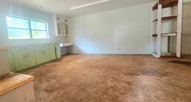 an empty room with chandelier fan and windows