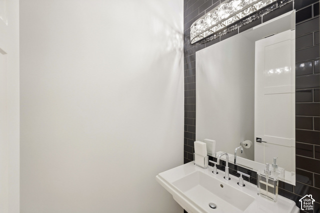 369 East Overlook Loop Kamas, UT 84036 - Photo 26 of 64 Pedestal sink with chrome faucet, large vanity mirror, and black subway tile accent wall