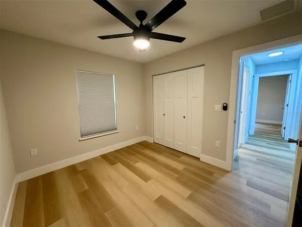 an empty room with wooden floor and a ceiling fan