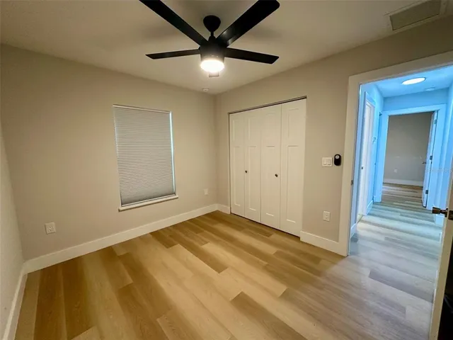 an empty room with wooden floor and a ceiling fan