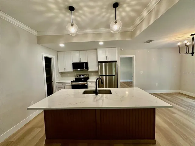 a kitchen with stainless steel appliances a kitchen island a stove a refrigerator a sink dishwasher a dining table and chairs with wooden floor
