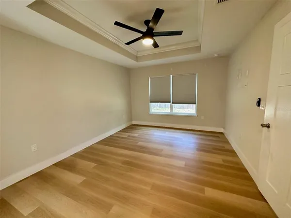 a view of empty room with wooden floor and fan