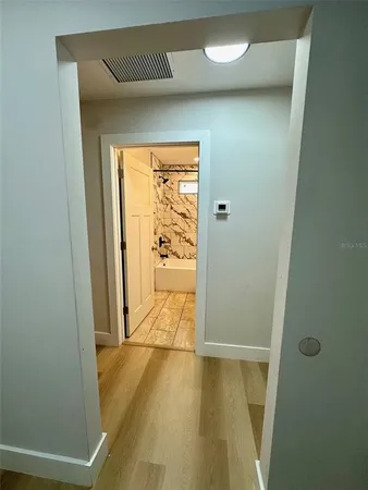 a view of an empty room with wooden floor and a window