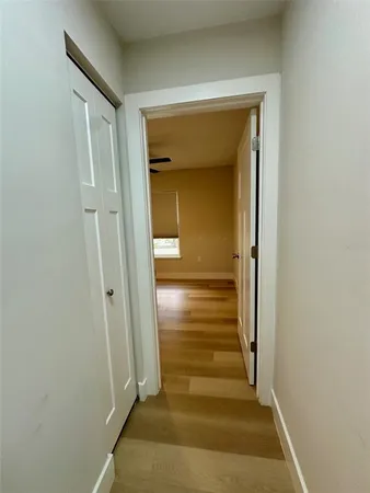 a view of a hallway with wooden floor and a bathroom