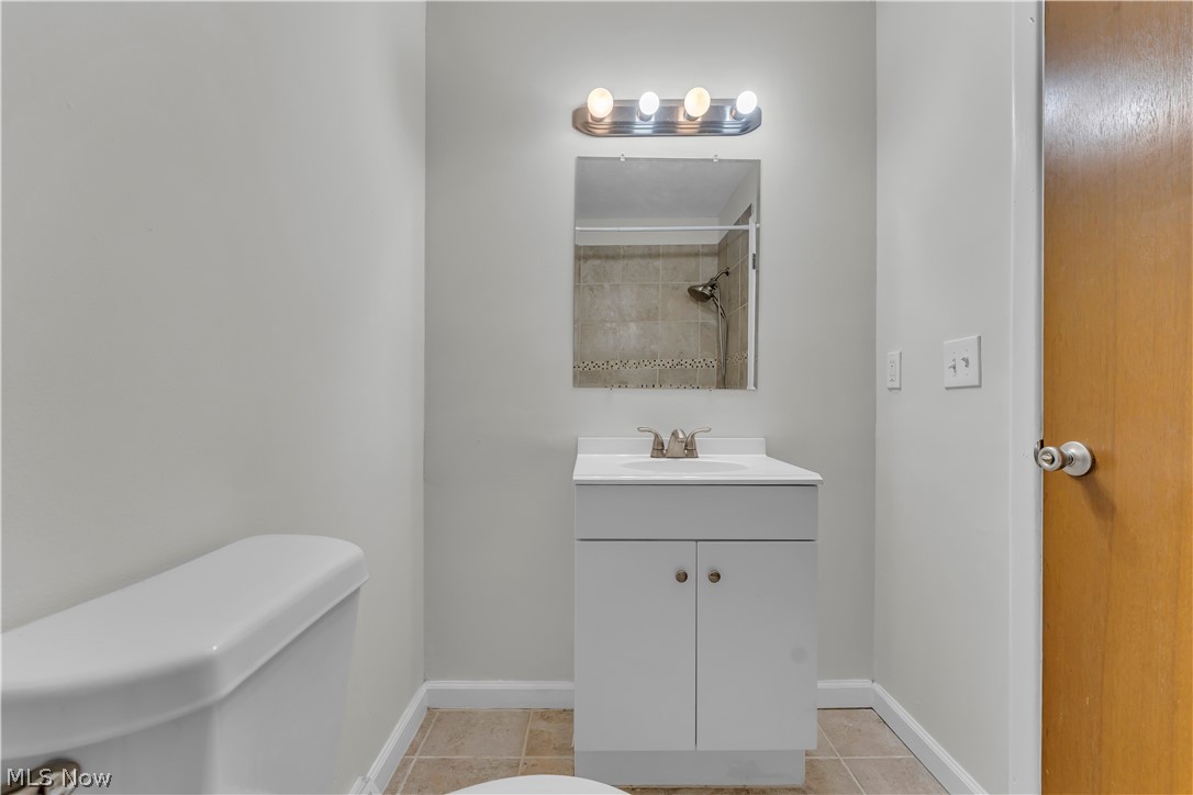 2540 Charney Road University Heights, OH 44118 - Photo 34 of 44 Bathroom featuring a single vanity with a white countertop and cabinet storage, a wall-mounted mirror, and a four-bulb light fixture