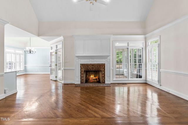 a view of an empty room with wooden floor fireplace and a window