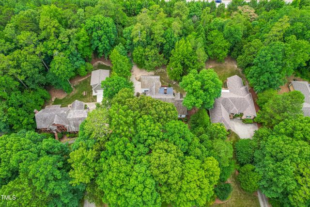 an aerial view of residential house with outdoor space and trees all around