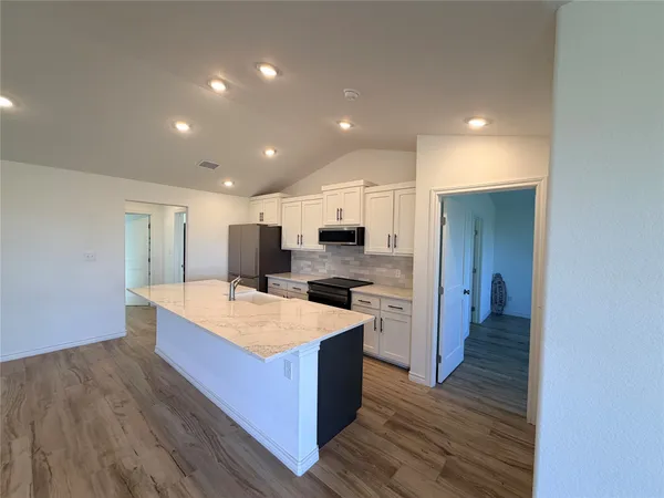 a kitchen with stainless steel appliances granite countertop a refrigerator a sink dishwasher a stove and a refrigerator