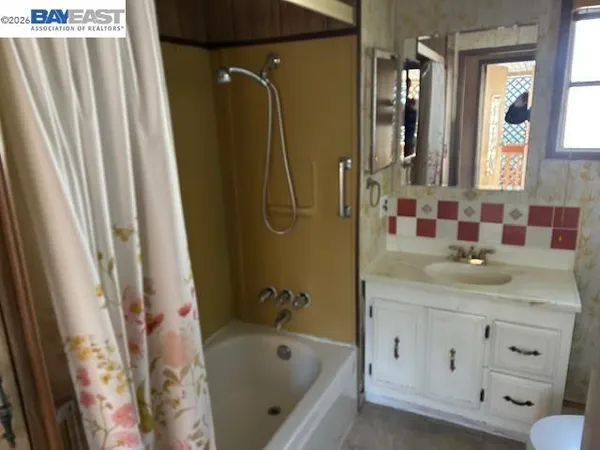 a bathroom with a granite countertop sink a mirror a vanity and a bathtub