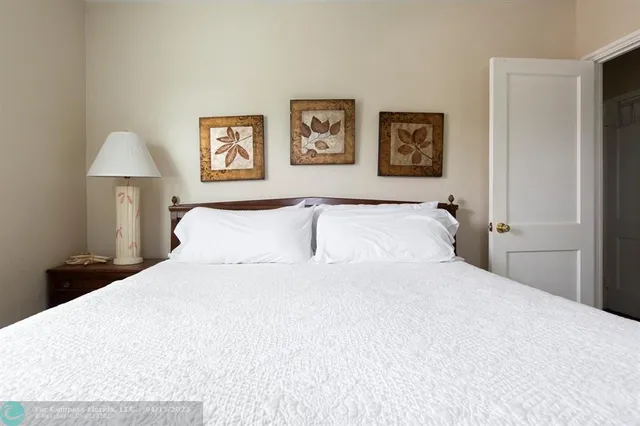 a large bed with a white comforter and painting on the wall