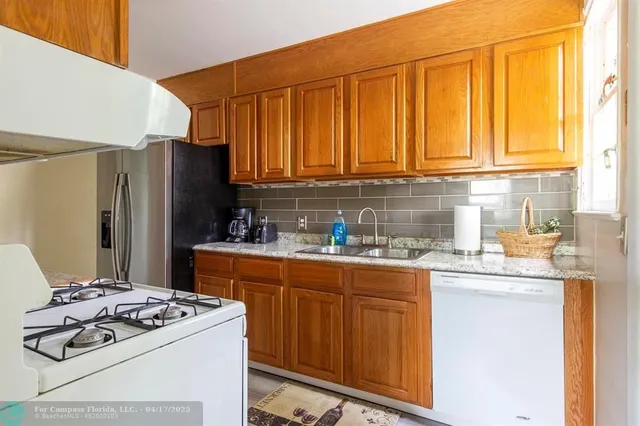a kitchen with stainless steel appliances granite countertop a stove a refrigerator and a sink