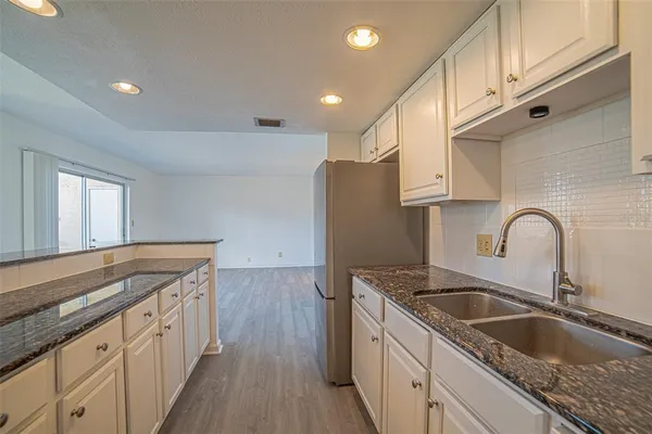 a kitchen with granite countertop a sink a refrigerator and wooden cabinets