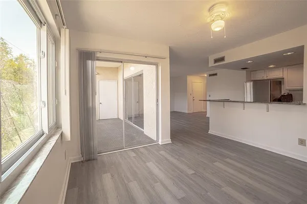 a view of a hallway with wooden floor and a kitchen