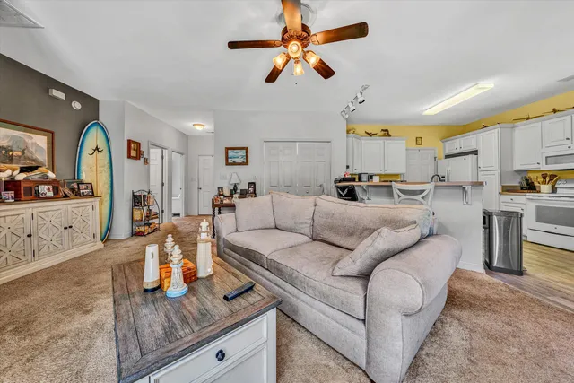 a living room with furniture kitchen view and a wooden floor