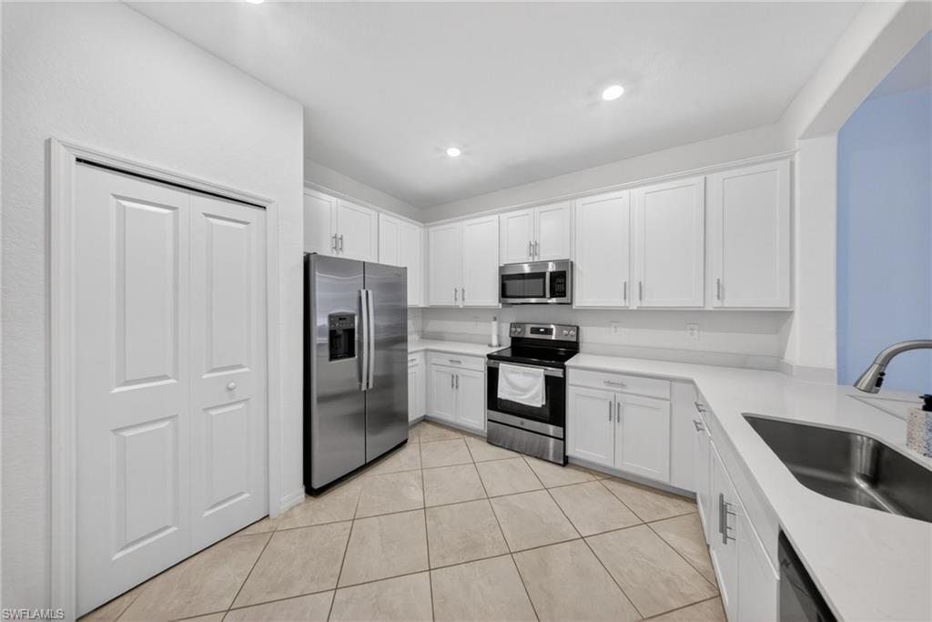 2196 Dragonfruit Way Naples, FL 34120 - Photo 6 of 50 a kitchen with white cabinets and stainless steel appliances