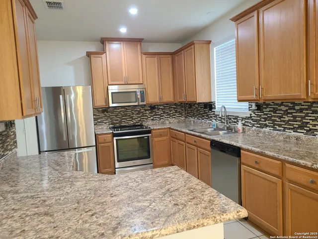a kitchen with granite countertop a sink stove and refrigerator