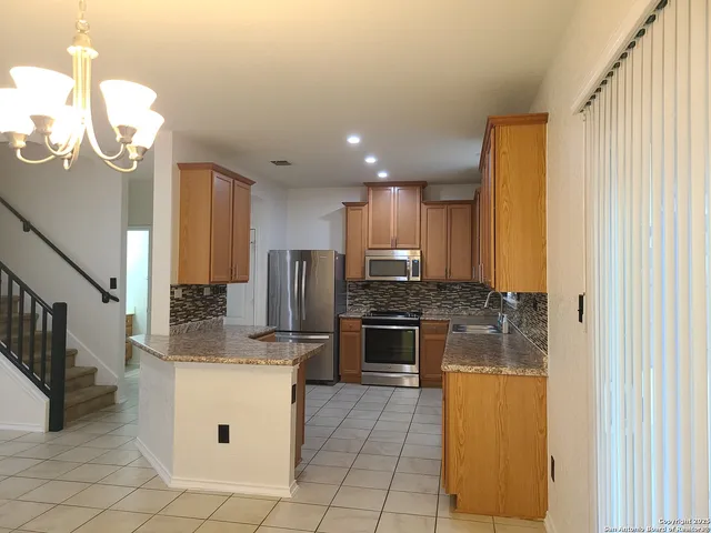 a kitchen with stainless steel appliances granite countertop a sink a stove a refrigerator and island with wooden floor