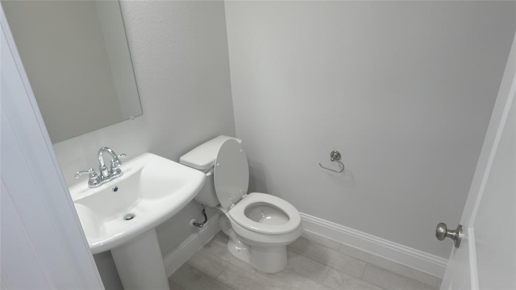 824 Heart Reef Road Plano, TX 75075 - Photo 16 of 19 Pedestal sink with chrome faucet, wall-mounted mirror, ceramic tile flooring, and a white commode