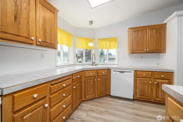a kitchen with stainless steel appliances granite countertop wooden cabinets a sink and dishwasher with wooden floor