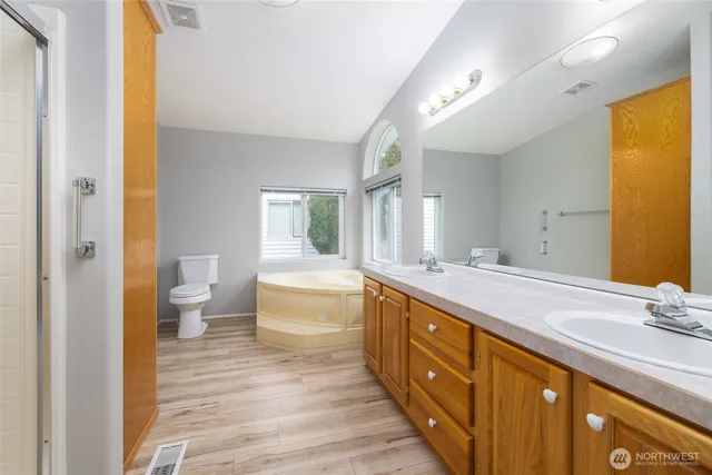 a spacious bathroom with a double vanity sink a large mirror and toilet