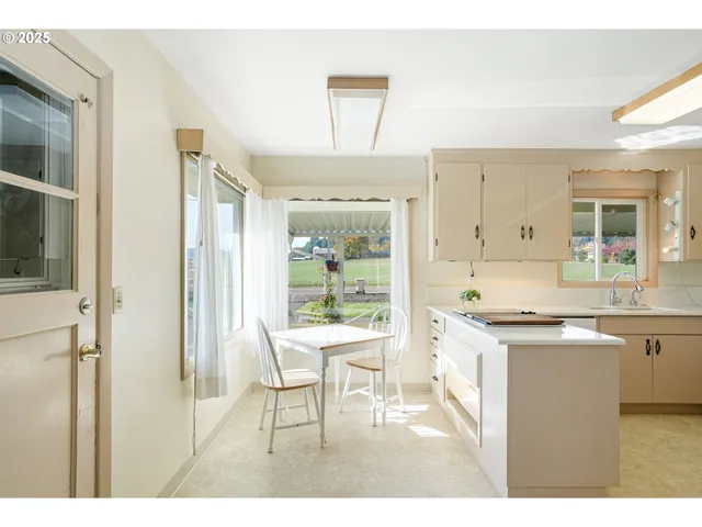 a living room with stainless steel appliances kitchen island a table chairs in it and a window