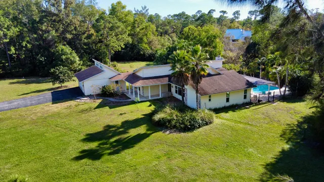 a view of a house with a big yard and large trees
