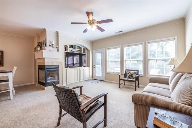 a living room with furniture a ceiling fan a fireplace and a large window