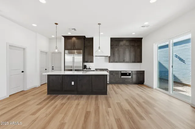 a large kitchen with a sink dishwasher a stove and a refrigerator with wooden floor