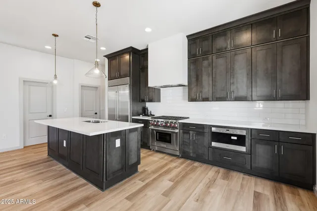 a kitchen with stainless steel appliances granite countertop a sink a stove and a wooden floors