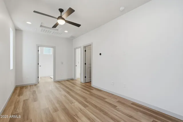 an empty room with wooden floor and a ceiling fan