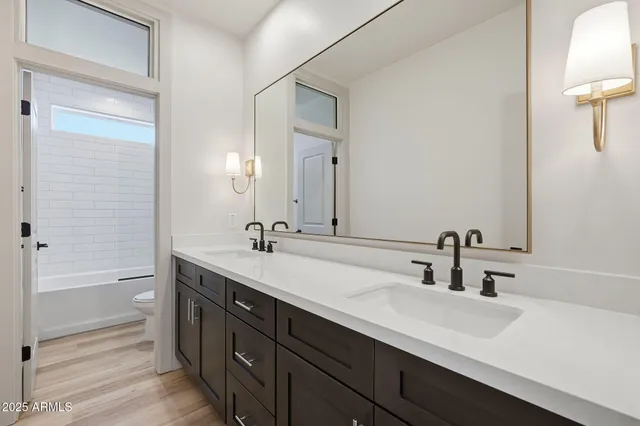 a bathroom with a double vanity sink a mirror and a bathtub