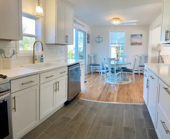 a kitchen with white cabinets appliances dining table and chairs