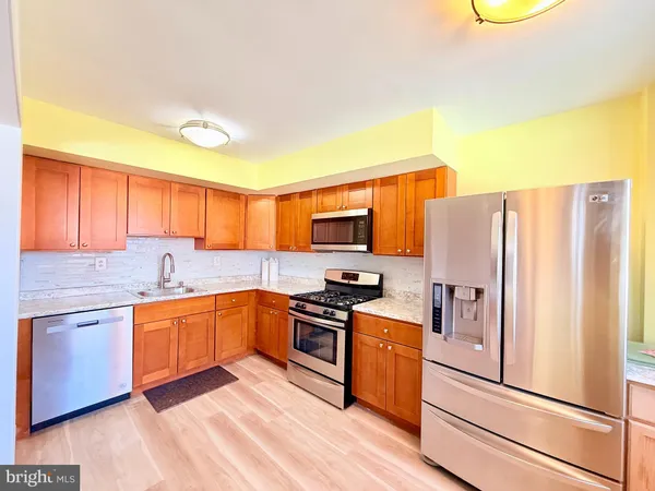 a kitchen with stainless steel appliances granite countertop a refrigerator a stove top oven a sink and dishwasher
