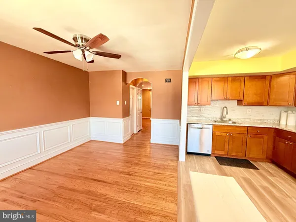 a view of a kitchen with kitchen island a sink wooden floor and stainless steel appliances