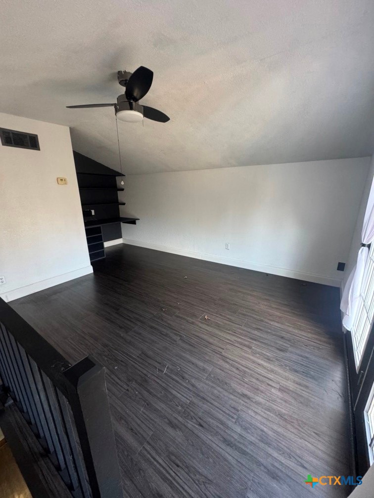 5524 Denmans Mountain Road Belton, TX 76513 - Photo 12 of 15 an empty room with wooden floor a ceiling fan and windows