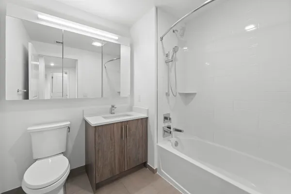 a bathroom with a bathtub shower sink mirror and toilet